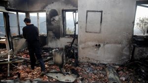 A man checks the damage to a house during a wildfire, in the communal settlement of Nataf, near Jerusalem November 23, 2016. REUTERS/Ronen Zvulun