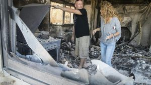 Relly (R) and Eyal Golan inspect the damage at their house, which burned during a wildfire caused by dry conditions, on November 23, 2016 in the northern Israeli town of Zikhron Ya'aqov. In Zikhron Ya'aqov, more than ten homes were burnt and several people have been lightly injured by smoke inhalation. / AFP / JACK GUEZ (Photo credit should read JACK GUEZ/AFP/Getty Images)
